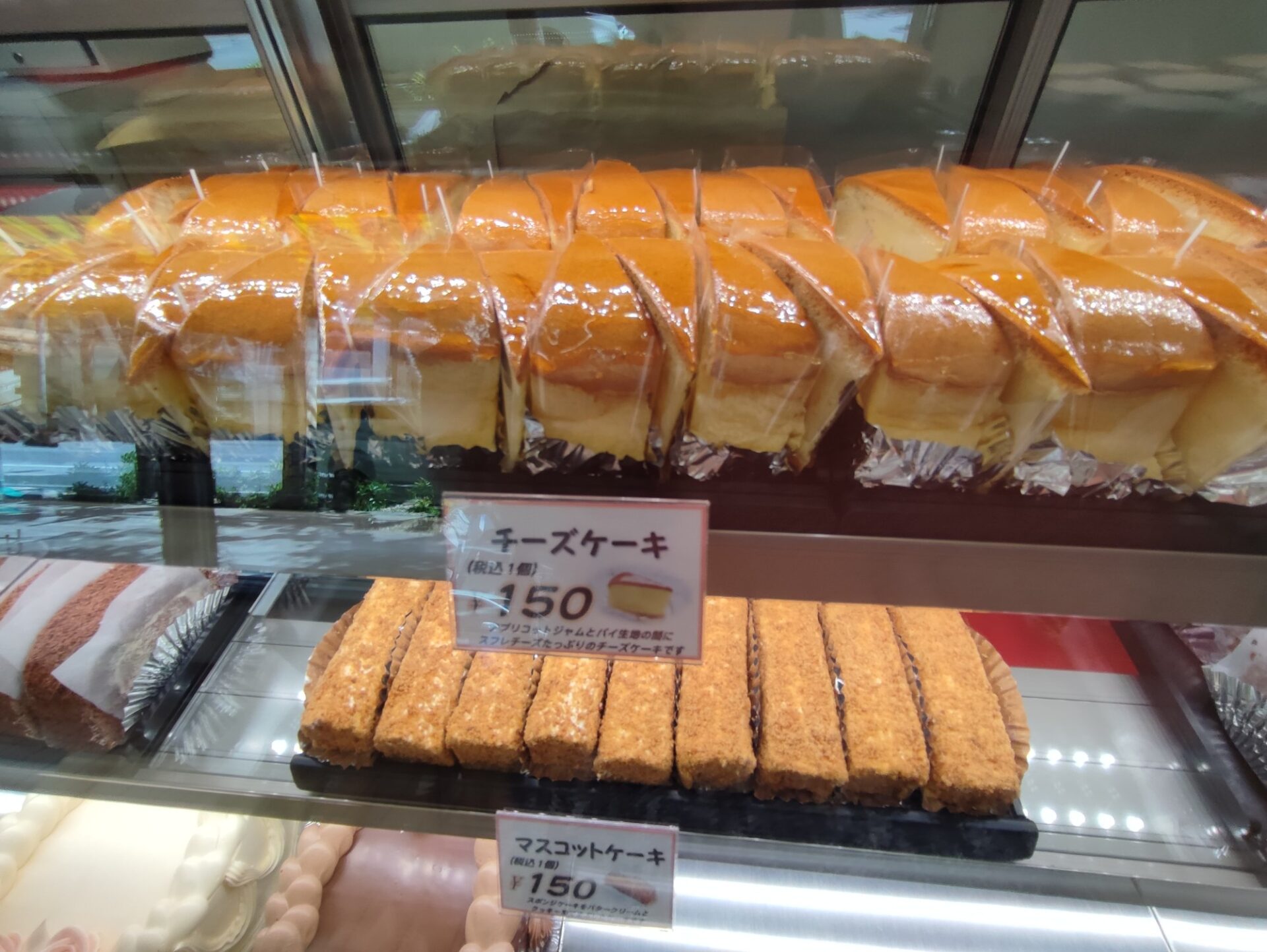 ショーケースの中の昔ながらのチーズケーキとマスコットケーキ