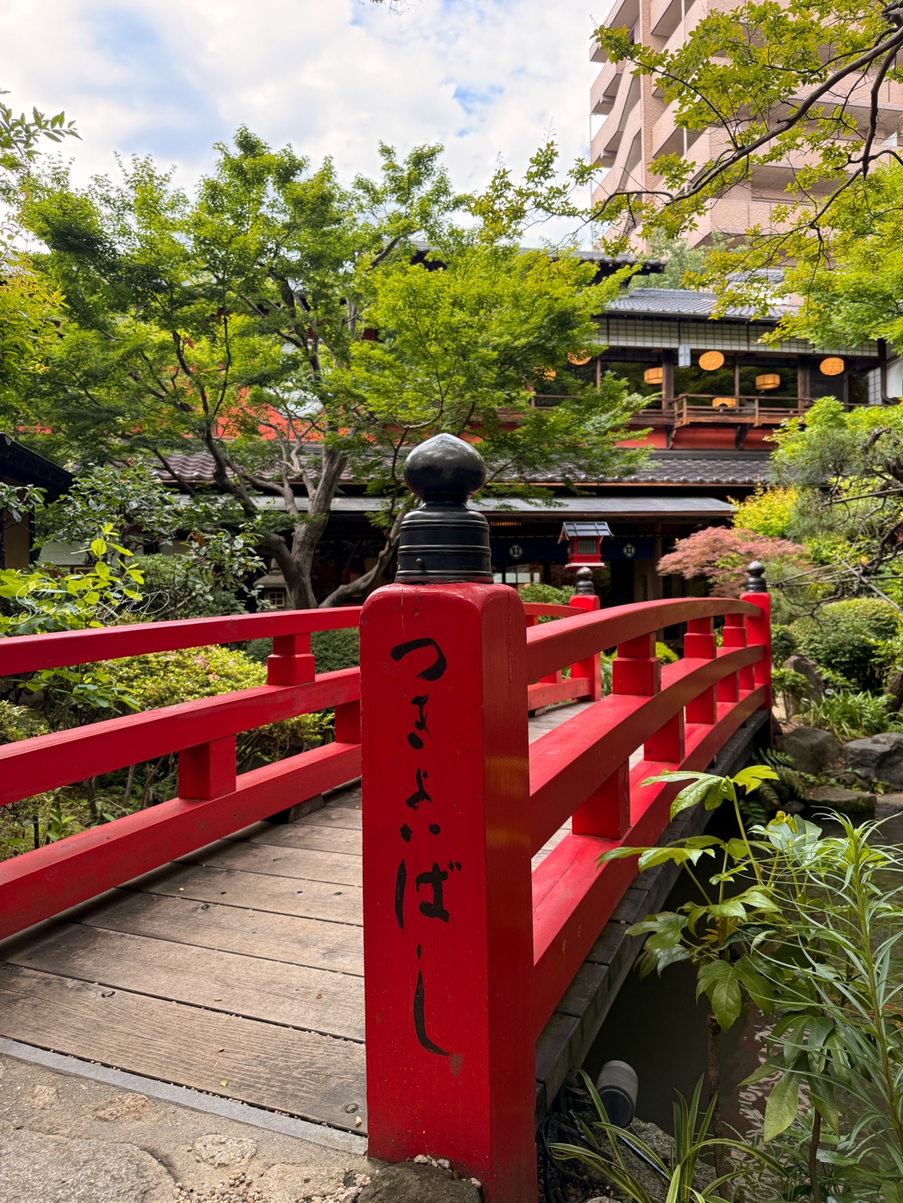 とうふ屋うかい 鷺沼店の日本庭園に架かる赤い橋と周囲の木々