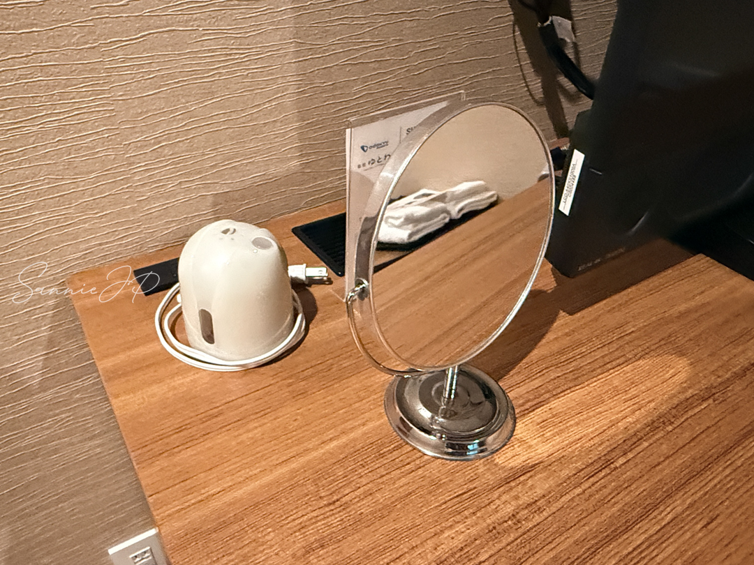 テレビ台横の鏡と蚊取り線香、コンセント。箱根ゆとわで女性ひとり旅にも使いやすい身支度スペース