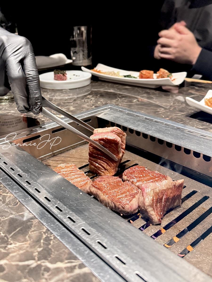 スタッフさんが丁寧に焼き上げる新進気鋭の焼肉。最適な火入れで香りが立ち、贅沢時間がゆっくり深まる様子。