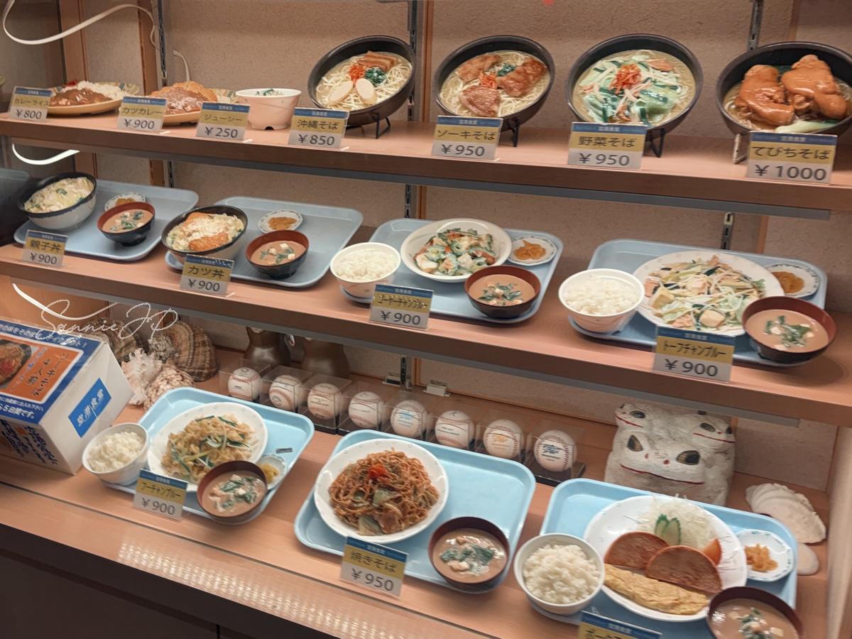 那覇空港の空港食堂らしい定食メニュー見本のアップで、ローカル感のある品ぞろえに期待が高まる一枚