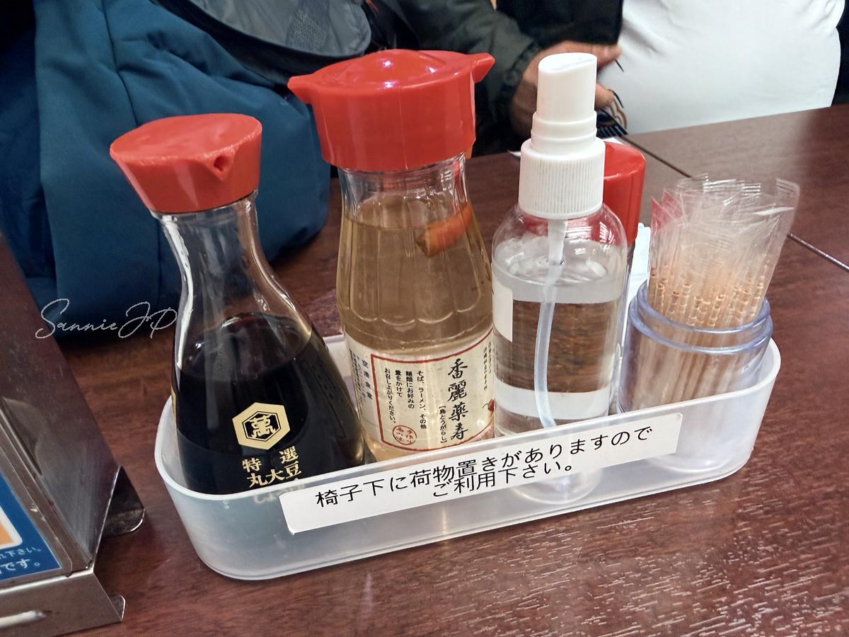 那覇空港の空港食堂テーブルに置かれた調味料セットで、コーレーグス入りの調味料が沖縄らしさを感じる