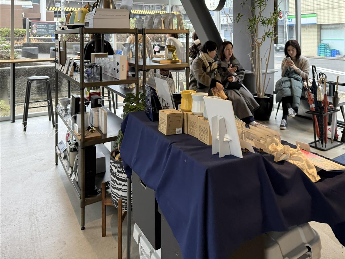 REC COFFEE 水道橋店の中央にあるグッズ売り場と待ち椅子。混雑時の様子が分かる店内